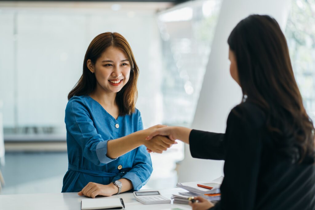 A woman and an interviewer shaking hands after a new job interview.