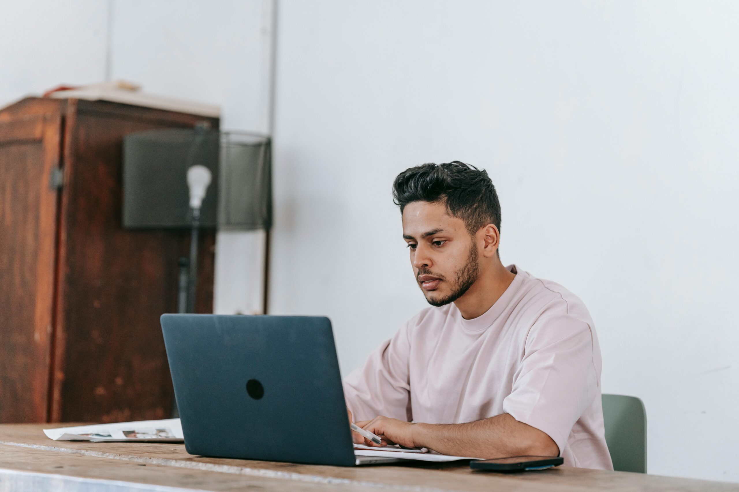 A young man using his laptop to search for available marketing internships.