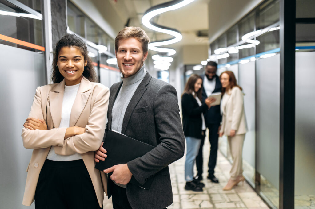 Two confident professionals in a modern office, representing stability, growth, and job security.